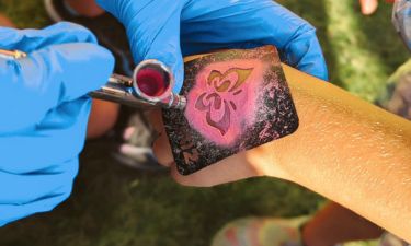 Child getting an airbrush tattoo on their hand