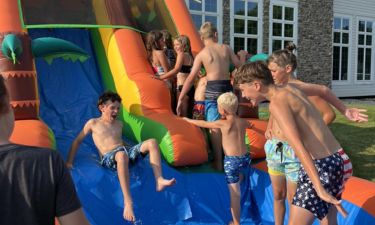 Children laughing while playing on an inflatable water slide