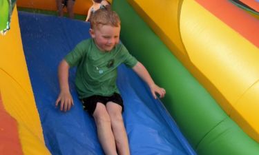 Child sliding down a water slide at a party