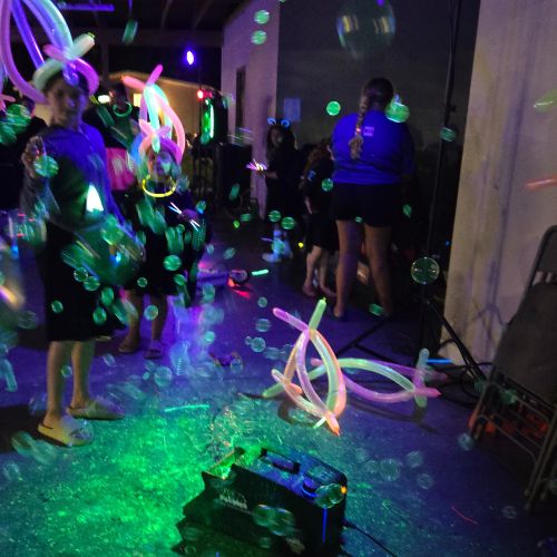 kinds dancing at a glow party with buble and fog machines