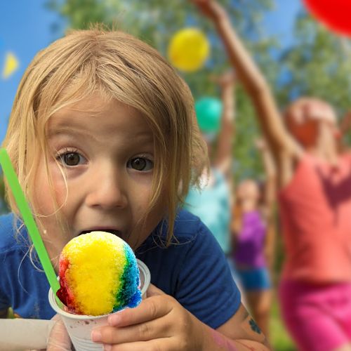 a little girl eating a snow cone at a birthday party